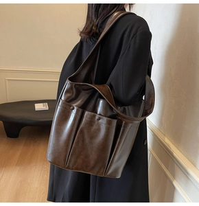 Detail of dark brown vintage PU leather tote bag with functional exterior pockets