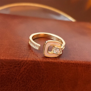 Macro detail of gold-plated pink enamel ring with cubic zirconia on brown leather surface