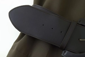 Close-up of olive green dress fabric texture and premium brown faux leather belt details