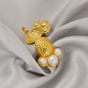 Golden octopus octopus textured earrings with white pearls on a purple silk background