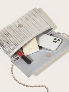 Dettaglio dell'interno della pochette plissettata argento con catena e trucchi