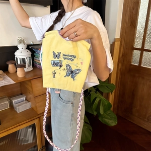 Détail du mini sac jaune avec broderie papillon bleue et bandoulière tissée colorée