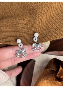 Macro shot of a silver horse earring with pearl inlay and shimmering pavé crystals