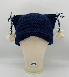 Detail of dark blue hand-knitted cat ear hat with striped tassels and white star charms