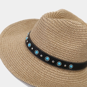Detail of straw fedora hat featuring black leather band with blue turquoise beads and silver studs
