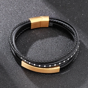 Detail of multi-layer black braided leather bracelet with brushed gold magnetic clasp