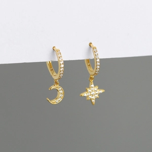 Detailed macro of gold asymmetric star and moon earrings with cubic zirconia pave