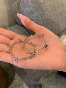 Close-up of silver bow hoop earrings held in hand showcasing the minimalist design