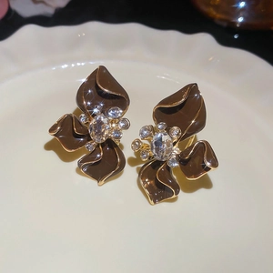 Close-up of coffee enamel flower earrings with sparkling rhinestones on ceramic tray