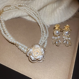 Detailed macro of vintage multi-layer pearl necklace and rose flower earrings in gift box