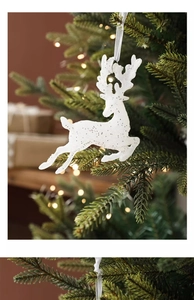 Détail d'un ornement de renne blanc pailleté suspendu à une branche de sapin