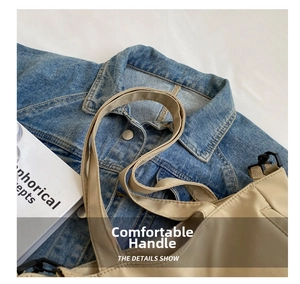 Detail of a beige tote bag with reinforced handles and black hooks on denim clothing