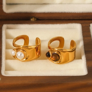 Close-up of gold hollow rings with pearls and tiger eye stones in a velvet box