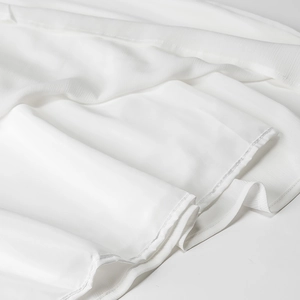 Détail de la texture du tissu en mousseline blanche et des coutures élégantes de la robe