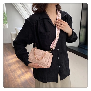 Detailed view of pink quilted handbag with acrylic chain and wide patterned strap