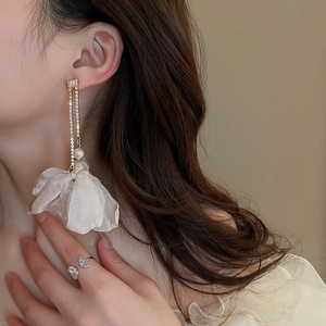 Detail of elegant gold tassel earrings with fabric flowers and sparkling rhinestones