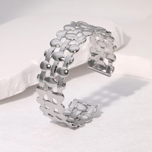 Silver stainless steel open bangle with hollow woven chain design on a white stone base