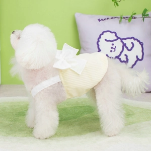 Detail of yellow knit pet dress with white shoulder straps and bow on a small dog