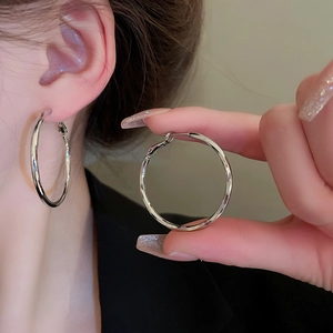 Detailed close-up showing the large silver metal hoop earring with a polished smooth finish