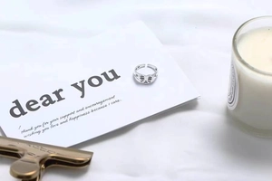 Detail view of silver open ring with unique crying face emoji on a clean background