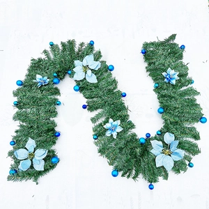 Detail of green Christmas garland featuring blue flowers and festive sphere ornaments