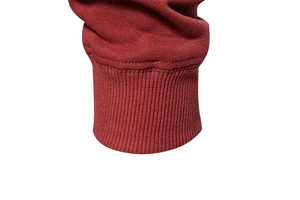 Detailed macro view of elastic ribbed cuffs on a dark red crewneck sweatshirt for men