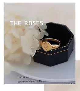 Detailed close-up of a gold rose signet ring displayed in a black velvet jewelry box