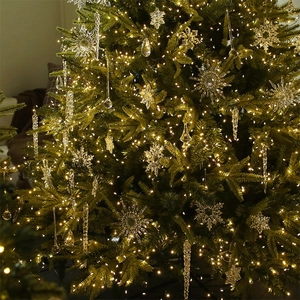 Clear acrylic snowflake and icicle ornaments with warm LED string lights on a Christmas tree