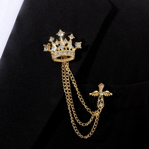 Gros plan sur broche couronne dorée avec croix ailée et chaînes de glands sur revers noir