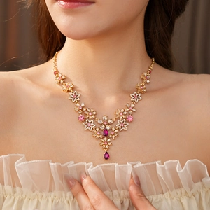 Detailed view of vintage gold floral necklace with pink rhinestones on a female model