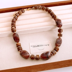 Détails d'un collier de perles vintage avec perles marbrées brunes et accents dorés
