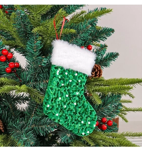 Close-up of green sequin Christmas stocking with white faux fur cuff on a tree