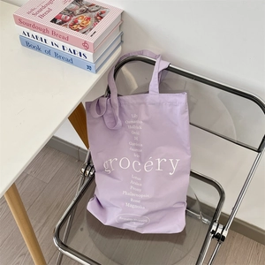 Détail du sac cabas en toile lavande avec imprimé floral posé sur une chaise chromée