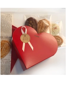 Detail of red heart-shaped gift box with white ribbon and assorted pastry set