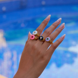 Detail of colorful enamel heart rings on hand with a turquoise swimming pool background