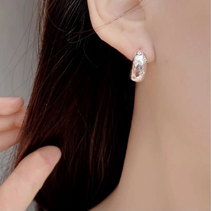 Close-up of S925 sterling silver hoop earrings with engraved stars and sparkling crystals