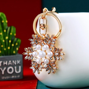 Detailed view of golden snowflake keychain with crystals and white pearls on desk