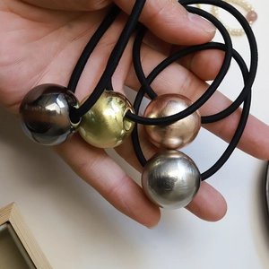 Close-up of elastic hair bands featuring brushed metallic spheres in gold, silver, and rose gold