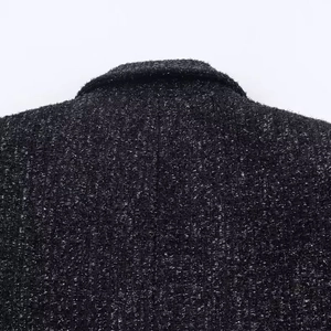 Close-up of premium tweed blazer fabric showing black and silver metallic weave detail