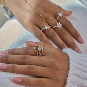Ensemble bracelet et bagues dorés avec zircons blancs porté avec un pull blanc doux