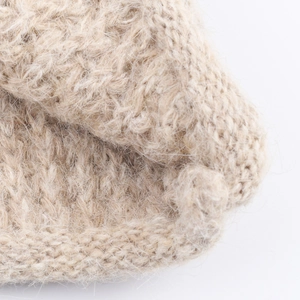 Close-up of thick beige chunky knit hooded sweater showing soft wool texture and patterns