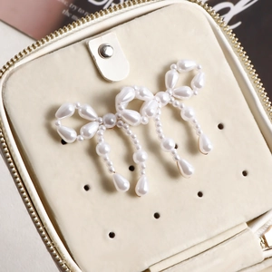 Detail of white faux pearl bow earrings with elegant tassels on jewelry box