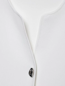 Detailed macro view of white textured knit fabric with unique silver irregular metal button