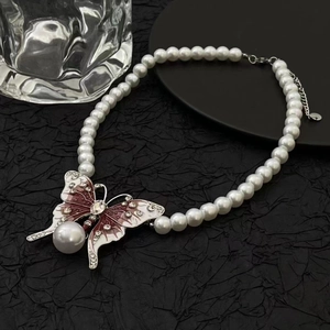 Détail du pendentif papillon en velours, émail rouge, cristaux et grande perle pendante