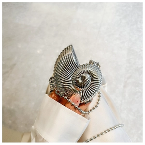 Close-up of a silver shell-shaped mini bag with textured metallic finish and bead chain