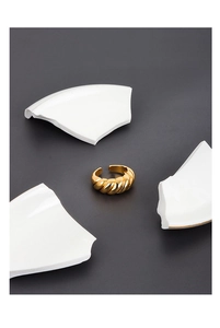 Macro shot of a gold croissant ring with twisted texture on a creative artistic background