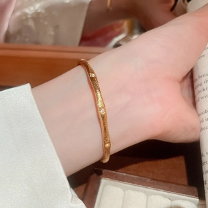 Macro shot of gold-plated wavy bangle with sandblasted finish and small zircon stones