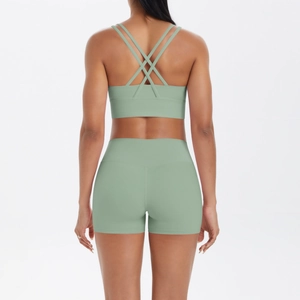 Détail du haut de sport vert sauge avec bretelles croisées et legging court de yoga