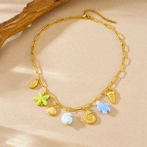 Gold ocean necklace with shell, starfish and sea turtle charms on sandy background