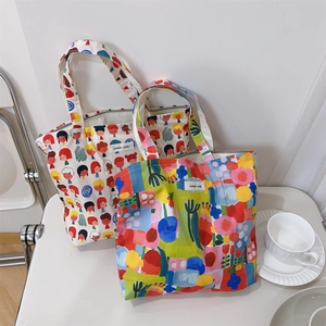 Detail of two canvas tote bags with cartoon and abstract prints on a white chair